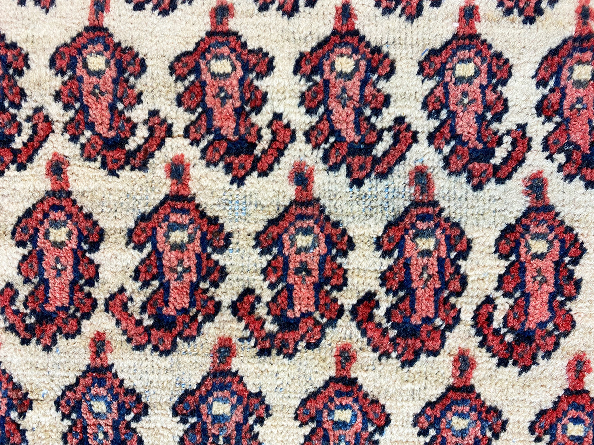 Gros plan sur le motif du tapis : médaillons répétitifs en rouge, bleu foncé et crème