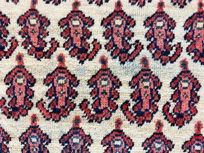 Gros plan sur le motif du tapis : médaillons répétitifs en rouge, bleu foncé et crème