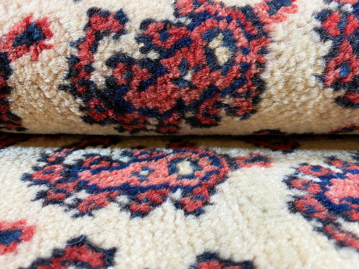 Gros plan : velours noué crème avec un motif dense de petites fleurs et d’ornements