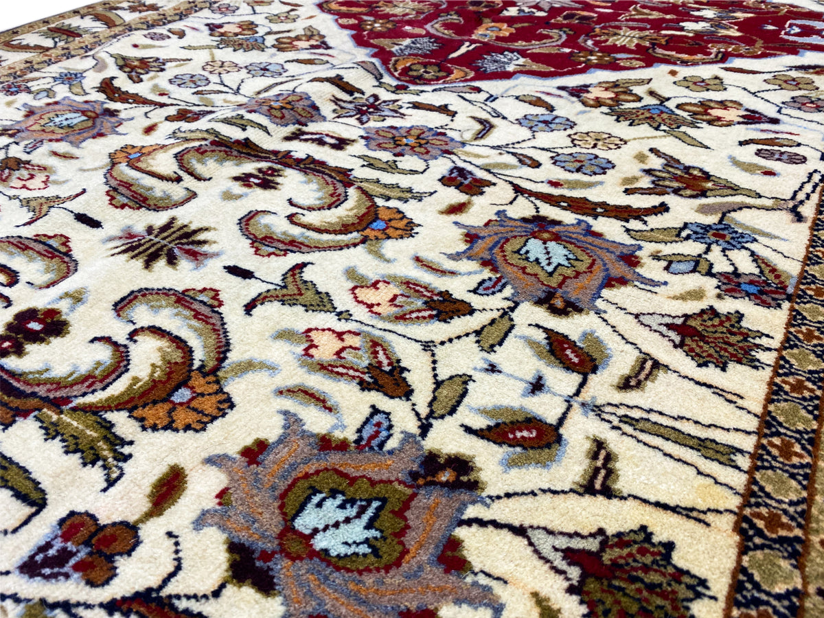 Gros plan d’un tapis baloutche : ornements colorés sur fond crème