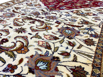 Gros plan d’un tapis baloutche : ornements colorés sur fond crème