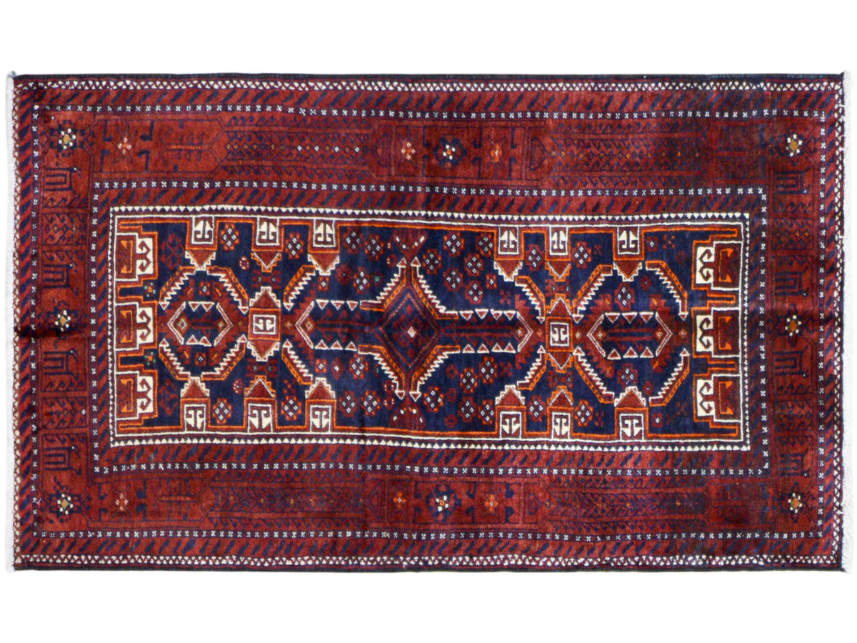 Tapis baloutche rectangulaire, rouge et bleu, avec champ ornemental central et bordure périphérique.