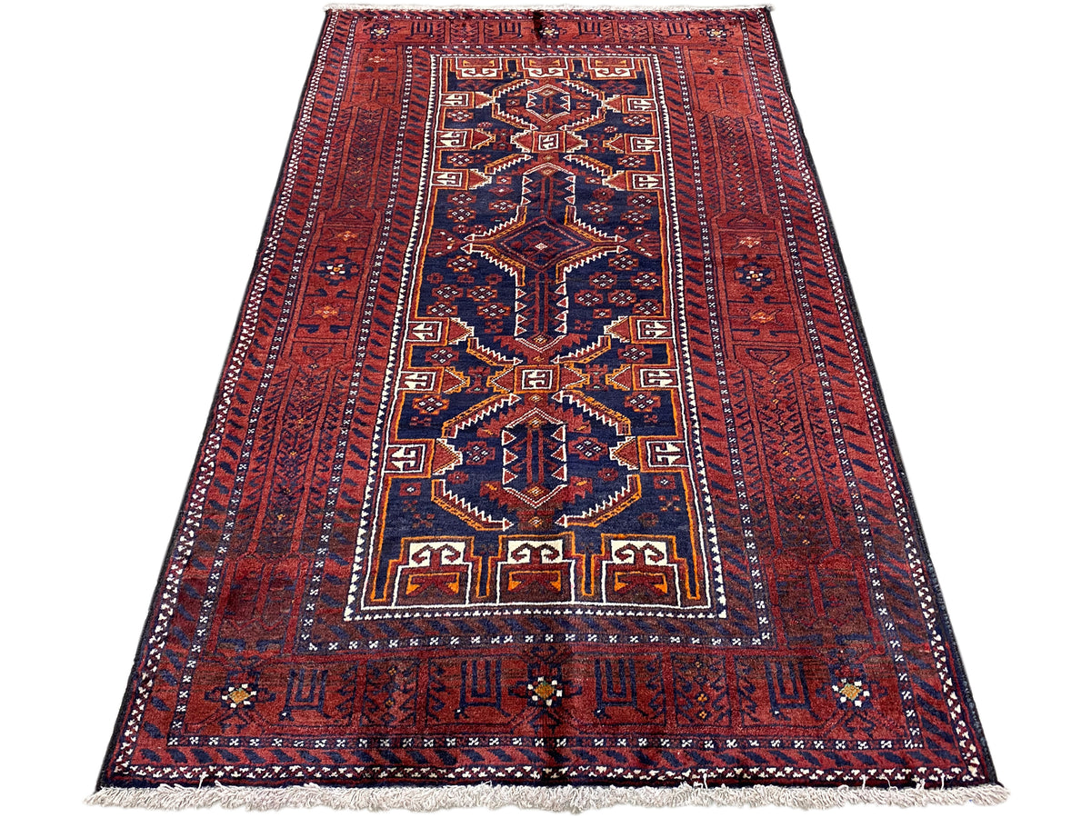 Tapis baloutche rectangulaire, rouge avec des ornements géométriques bleu et or, à franges.