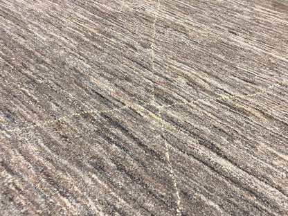Nahaufnahme: melierte Teppichoberfläche in Grau-Beige mit goldfarbenen Fadenakzenten und Linien.