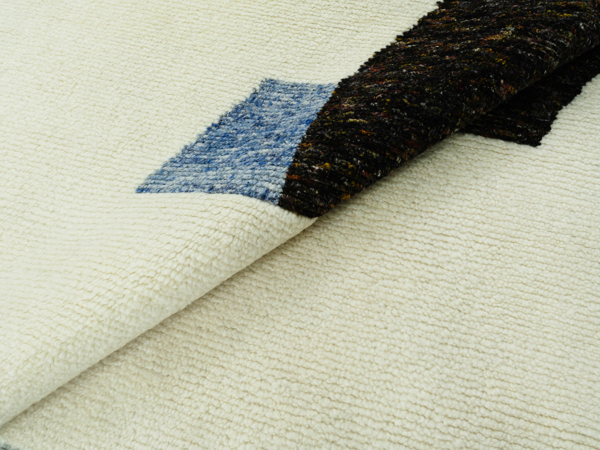 Teppich ausgebreitet: sichtbare Struktur und ein gerollter Bereich mit Blau-Schwarz-Element