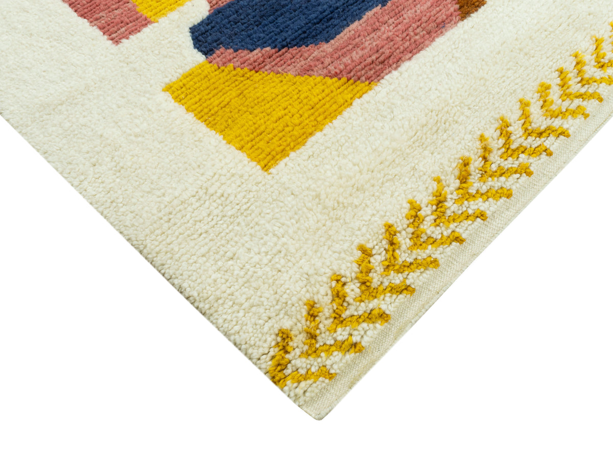 Ecke eines Teppichs: cremefarben mit Patchwork-Quadraten und gelber Zackenbordüre