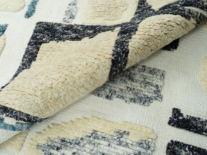 Teppich 240x170 cm Nahansicht: gepolsterte Florflächen in Creme, Blau und Schwarz, Fransen