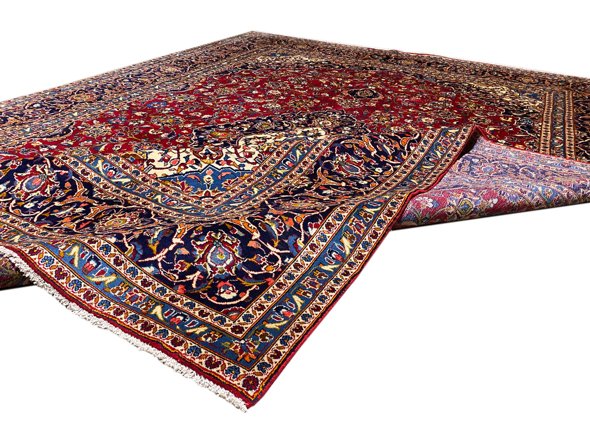 Orientteppich-Ecke mit rotem Grund, blauem Bordürenmuster und weißen Fransen