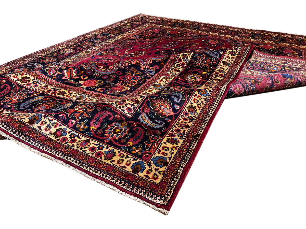 Teppich in Dunkelrot mit blauem Zentrum, ornamentalem Rahmen und Medaillon