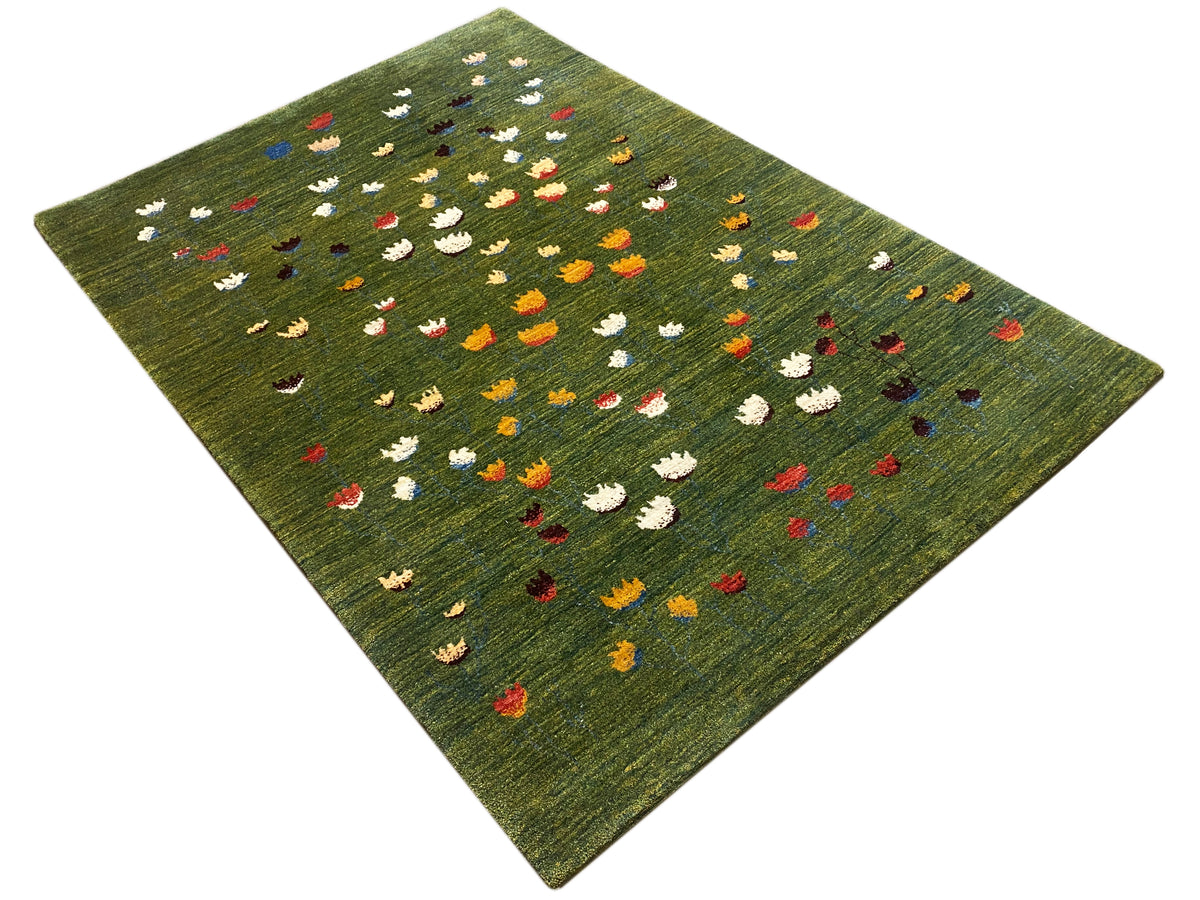 Olivgrüner Teppich mit bunten Blumenmotiven, von oben im diagonalen Blick