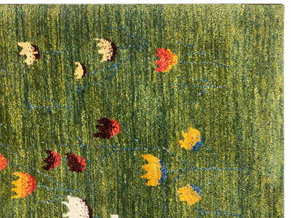 Nahaufnahme: Olivgrüner Teppich mit blauem, gelbem und rotem Blumenmuster