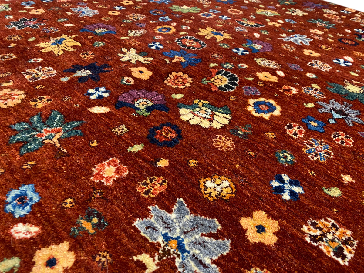 Nahansicht Teppichoberfläche: rötlich-braun mit mehrfarbigen Blüten und Ornamenten.