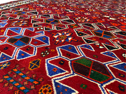 Detailaufnahme der Oberfläche: rotes Muster aus Rauten und Sternen in Blau, Grün und Beige