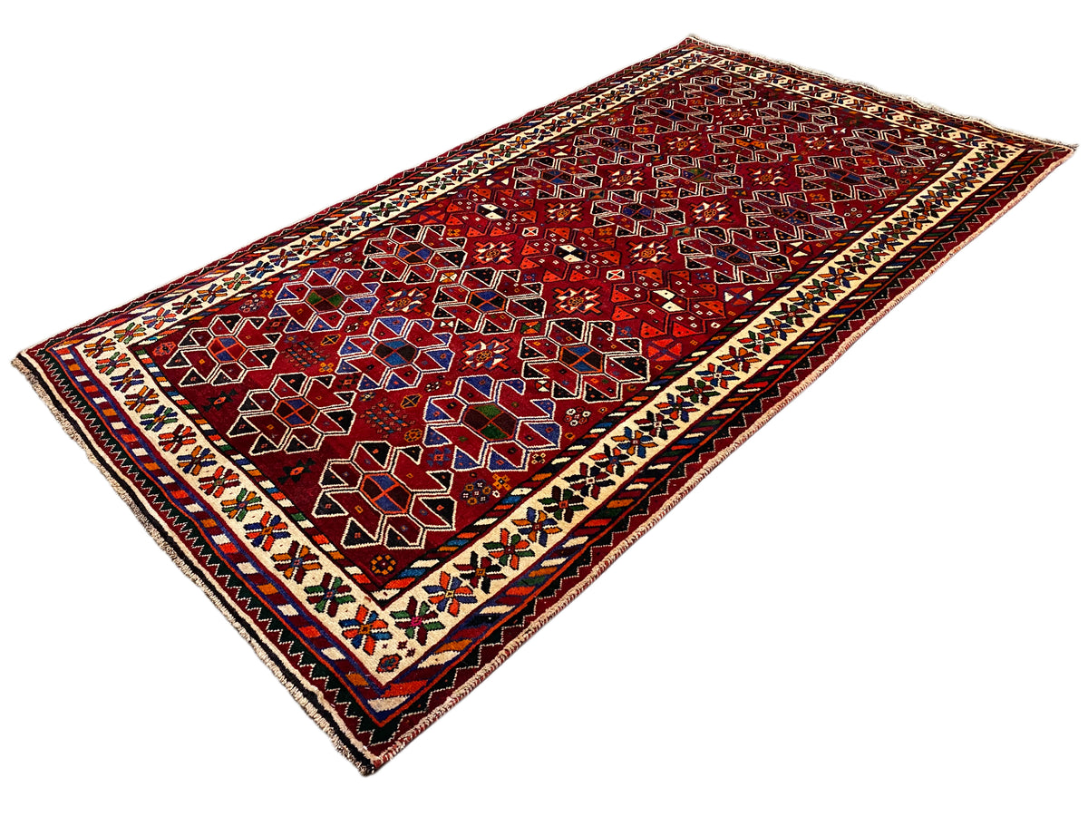 Orientteppich in Schrägansicht mit rotem Design, Bordüre mit mehrfarbigen Zacken