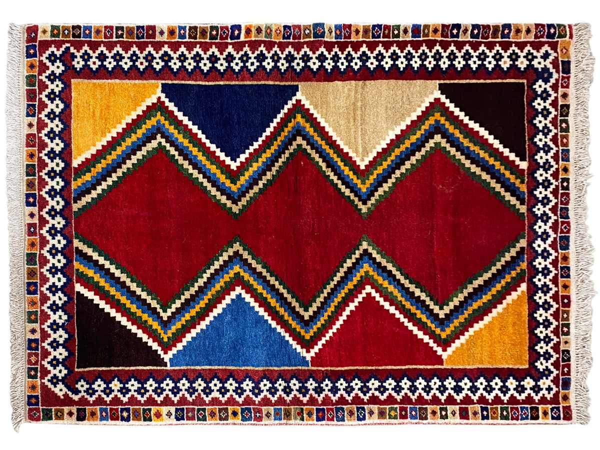 Rechteckiger Shiraz-Teppich mit Zickzack- und Rautenmustern in Rot, Blau, Gelb und Beige, Fransen.