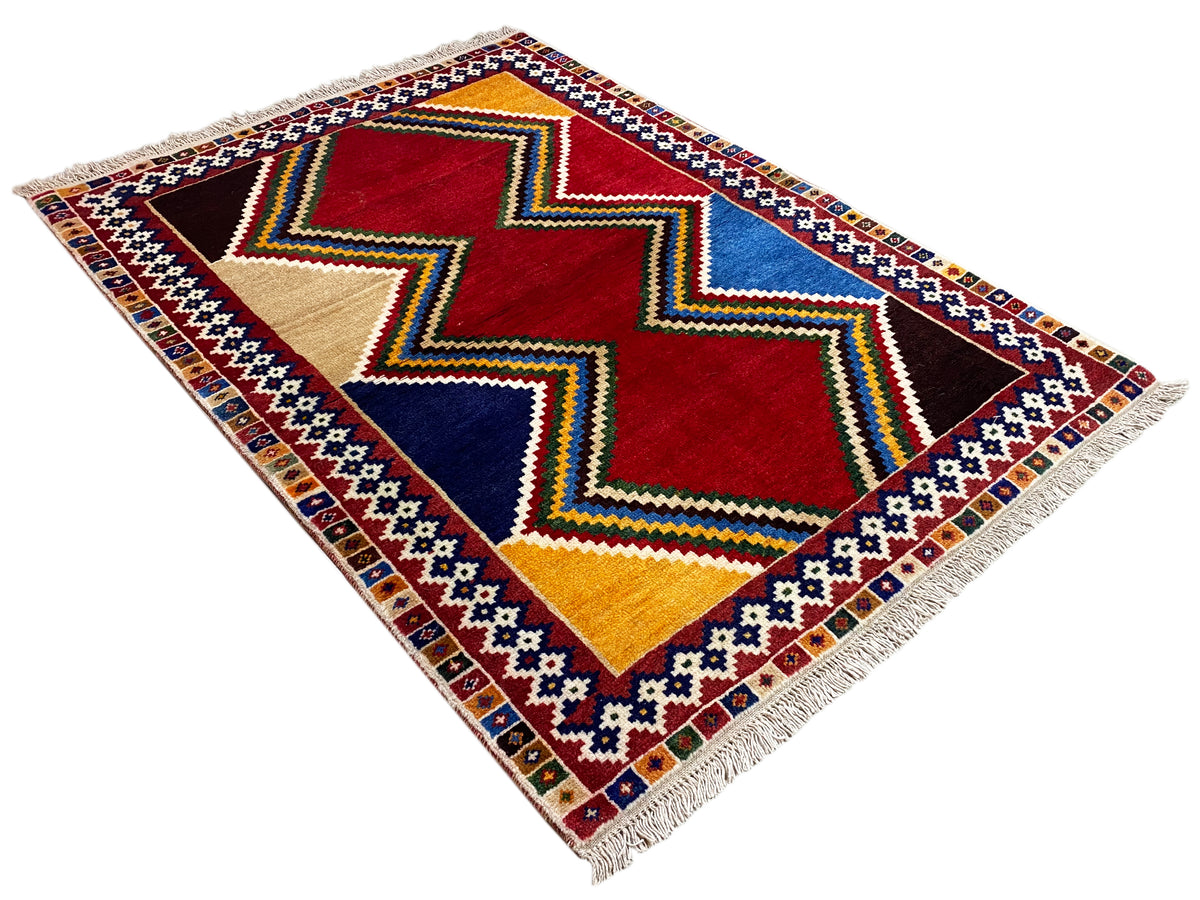 Shiraz-Teppich quadratisch mit Rauten- und Zickzackmustern in Rot, Blau, Gelb, Beige, Fransen.