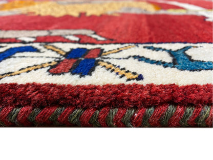 Teppich-Detail mit roter Floroberfläche, farbigen Mustern und seitlichem Fransenabschluss