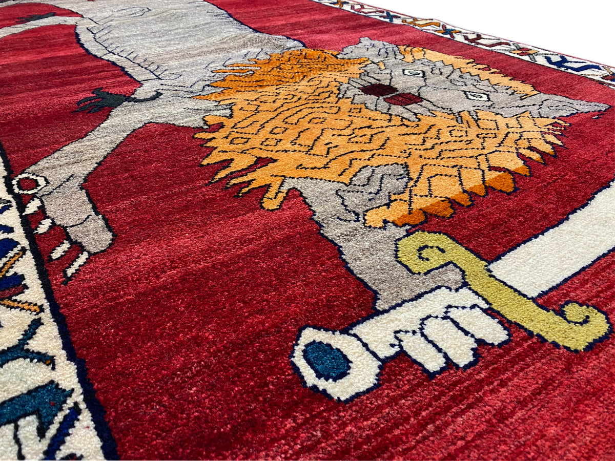 Teppich-Detail: graues Tier und orangefarbenes Ornament auf rotem Grund