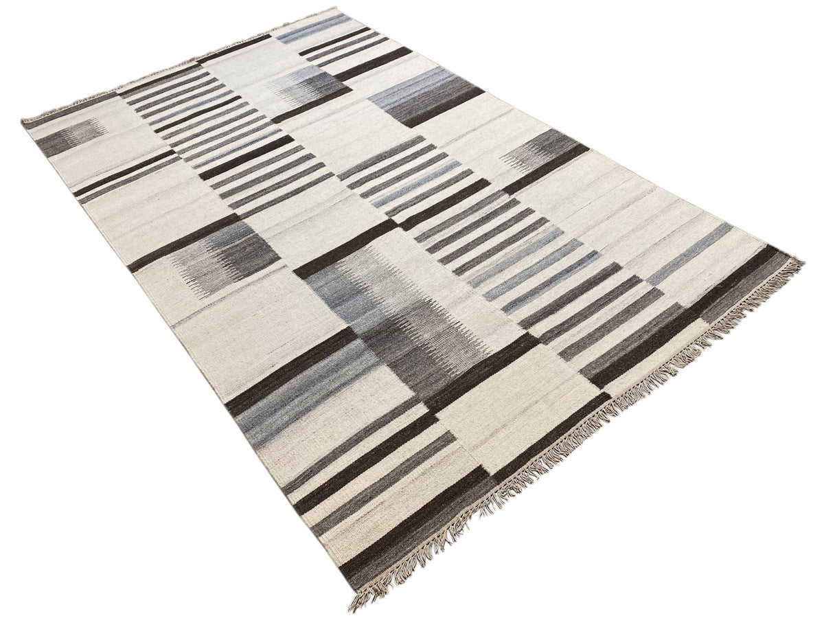 Kelim-Teppich in Creme und Grau mit Patchwork-Quadraten und Streifen, diagonale Ansicht, Fransen.