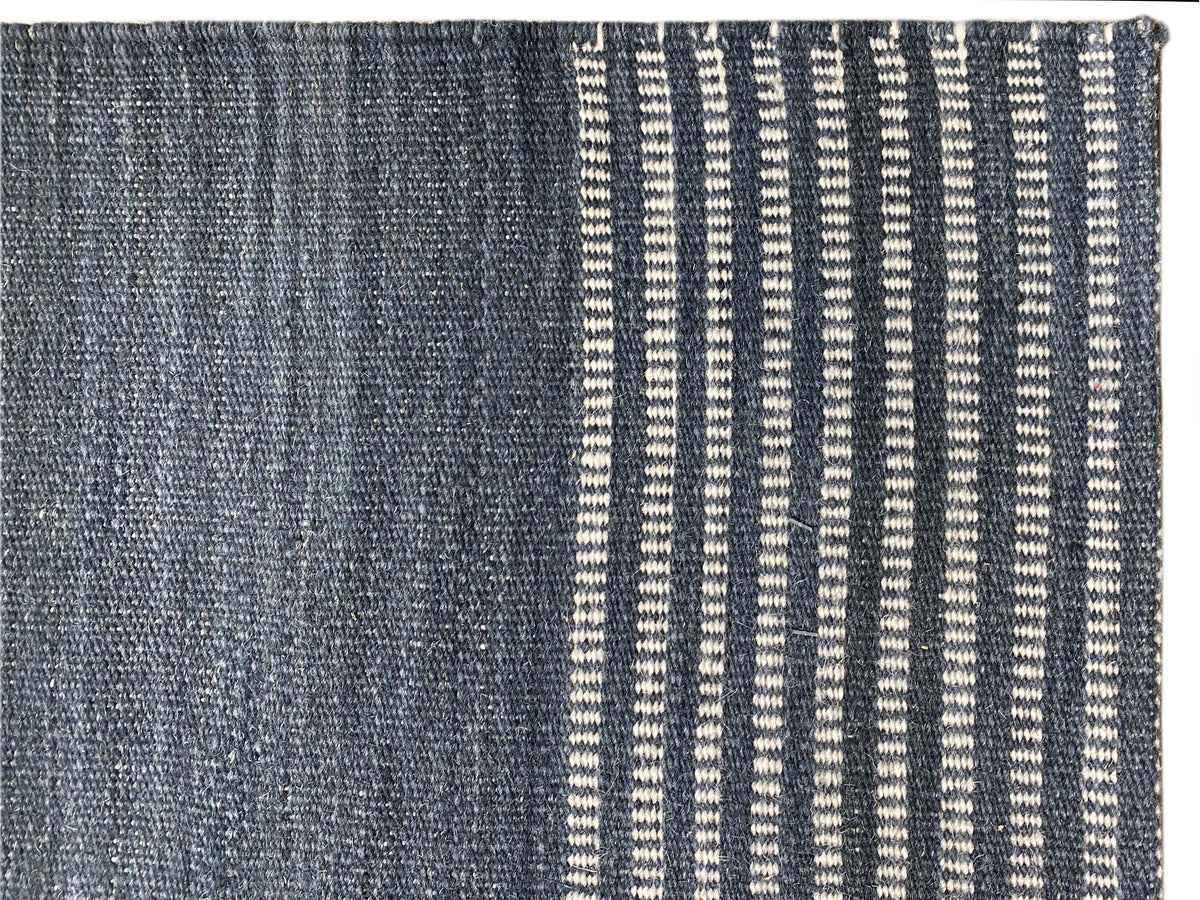 Kelim Teppich-Detail mit sichtbarer Struktur und schmalen weißen Streifen auf Blau