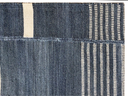 Detail vom Kelim-Teppich: dunkelblaue Flächen, beiger Rand und feine Streifenstruktur